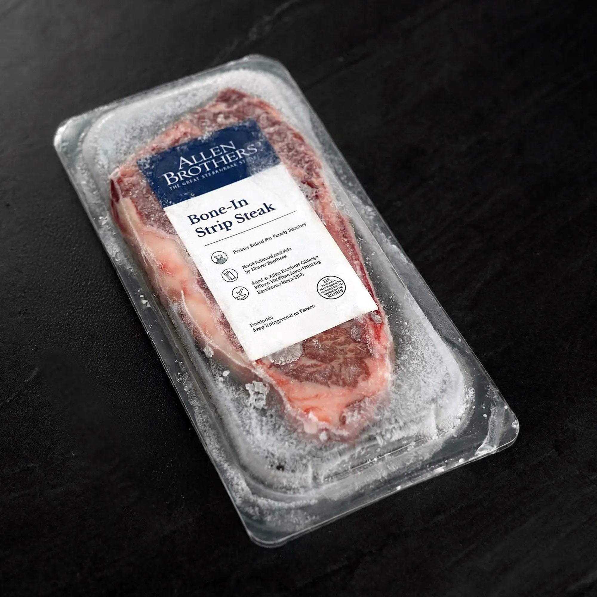 Vacuum-sealed frozen bone-in New York strip steak from Allen Brothers, displayed on a dark countertop, highlighting its quality and freshness.