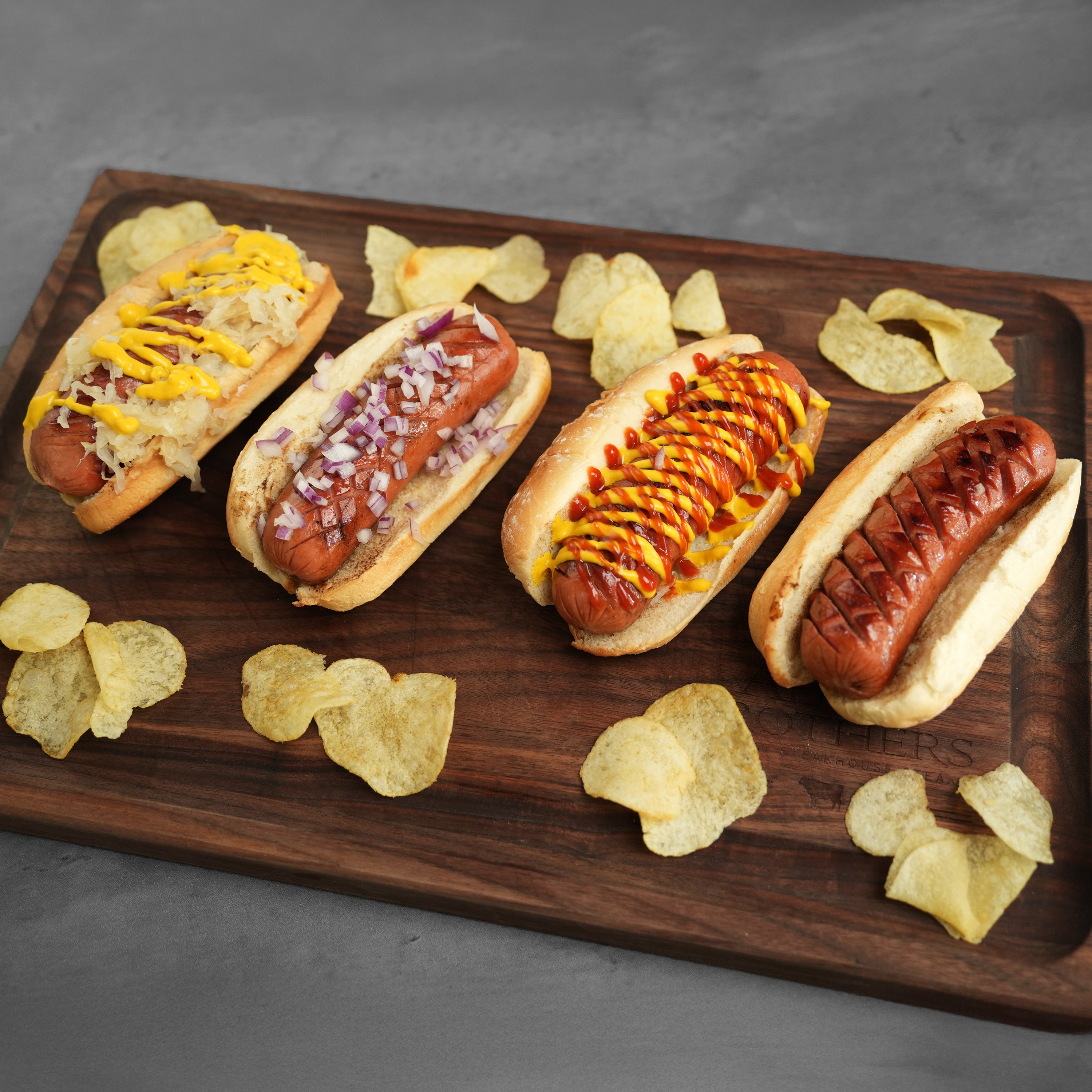 All-American Combo featuring four Chicago-style hot dogs with varied garnishes on a wooden board, showcasing juicy, flavorful, all-beef skinless Steak Dogs ready to serve.