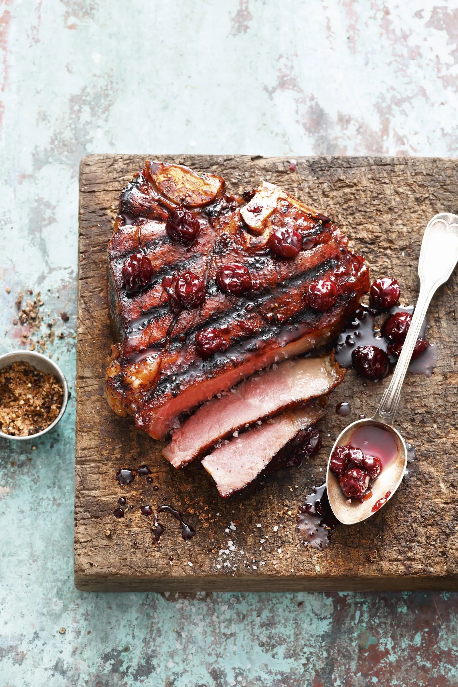 Cooked meat on wood board with spoon and sauce