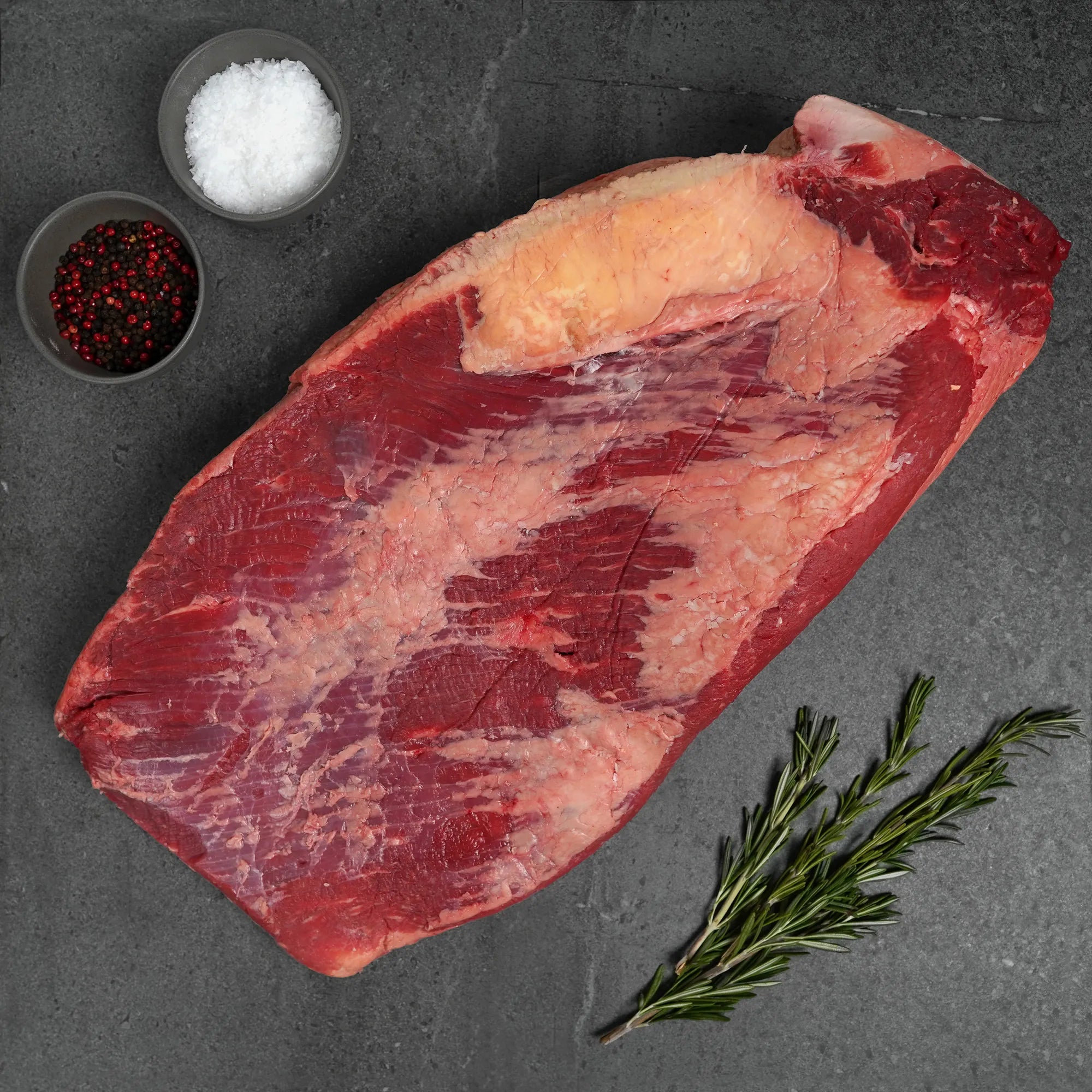 raw meat on grey surface with salt and pepper garnish