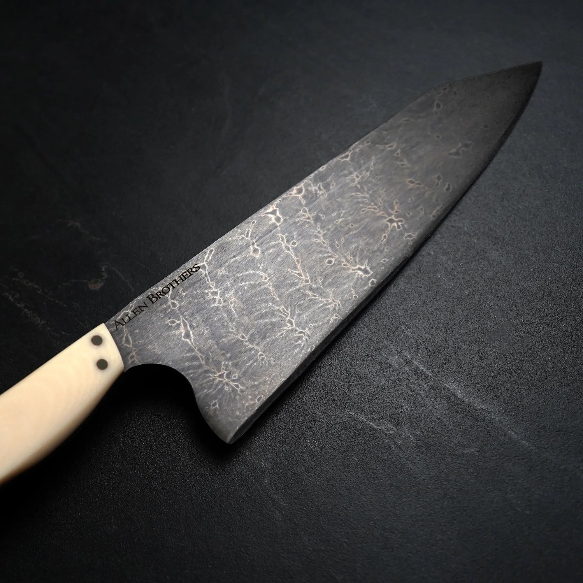 metal knife with white handle on dark surface