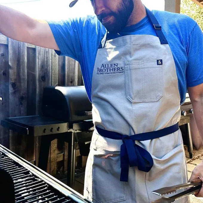 man wearing apron outside next to grill