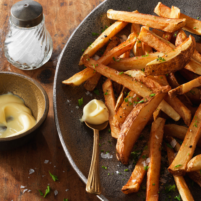french fried potatoes on plate with spoon and salt garnish