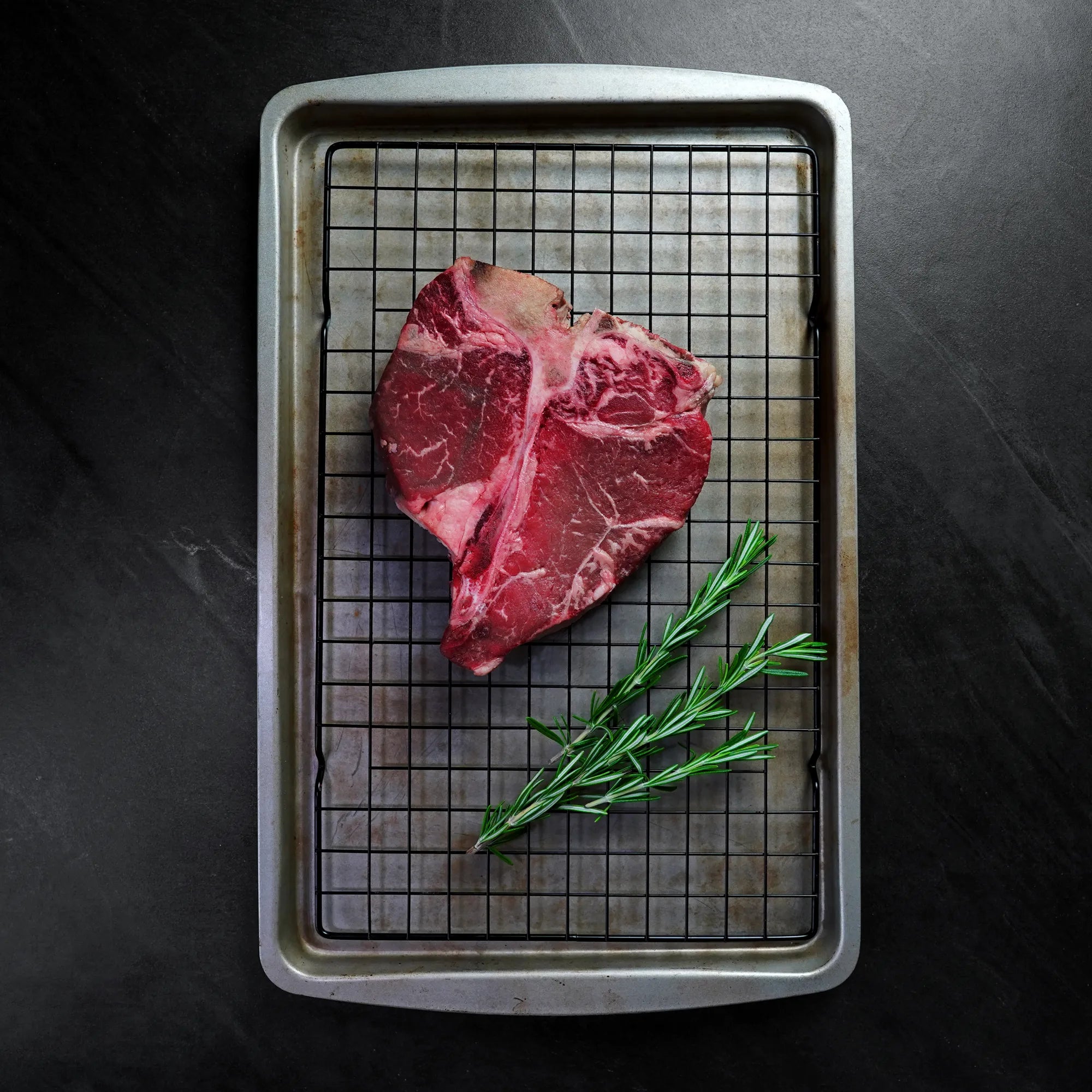 Raw Angus Porterhouse on baking sheet