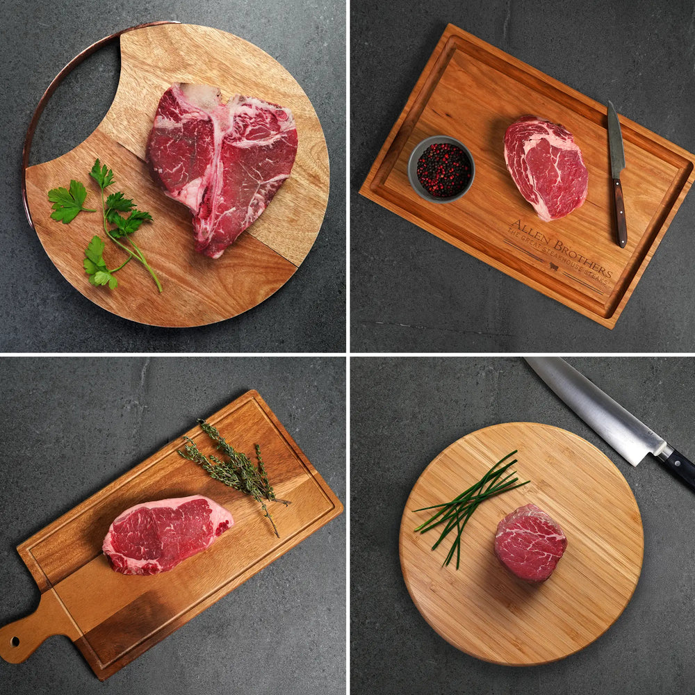 Steak Lovers Choice Angus Combo: T-bone, ribeye, strip steak, and tenderloin filet artfully arranged on boards, showcasing premium cuts with herbs and tools.