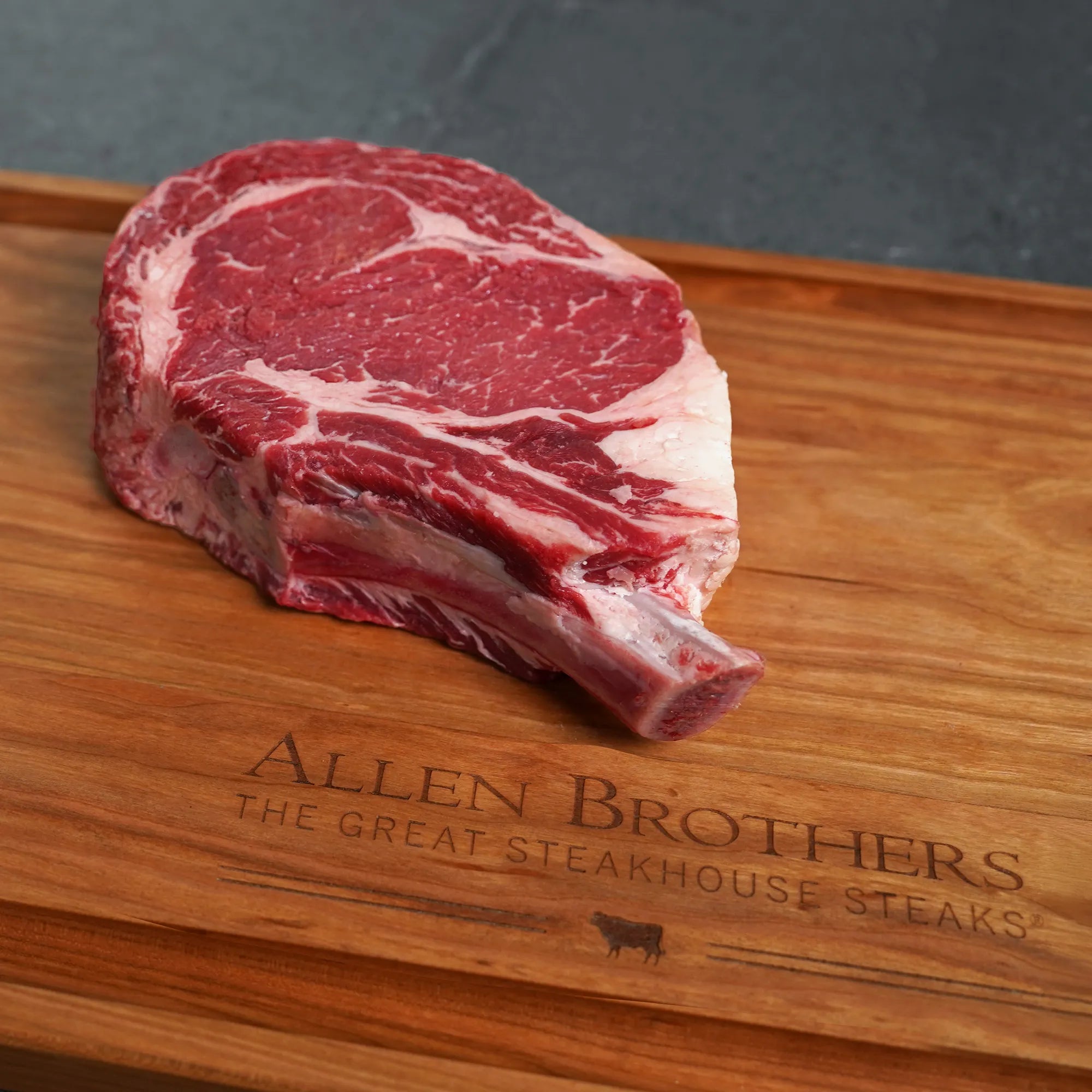 Raw steak on a wooden cutting board with 'Allen Brothers' branding.
