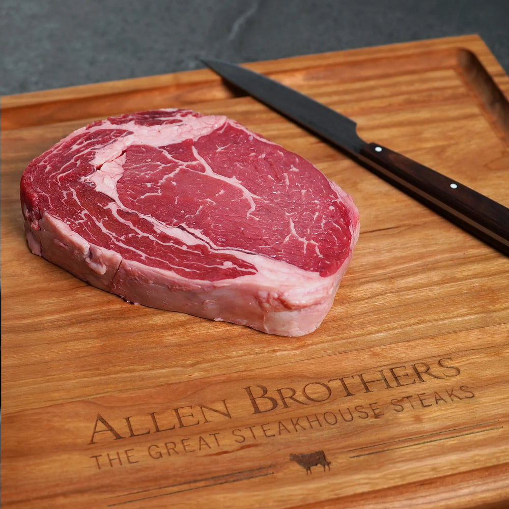Steak Lovers Choice Angus Combo: Close-up of a marbled ribeye on a board with Allen Brothers logo, showcasing premium, hand-cut Black Angus steaks.