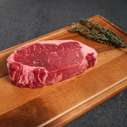 Raw steak on a wooden cutting board with a dark background