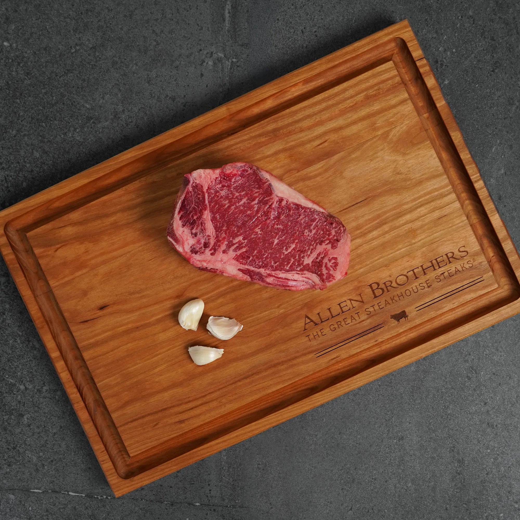 Raw steak on a wooden cutting board with 'Allen Brothers' branding.