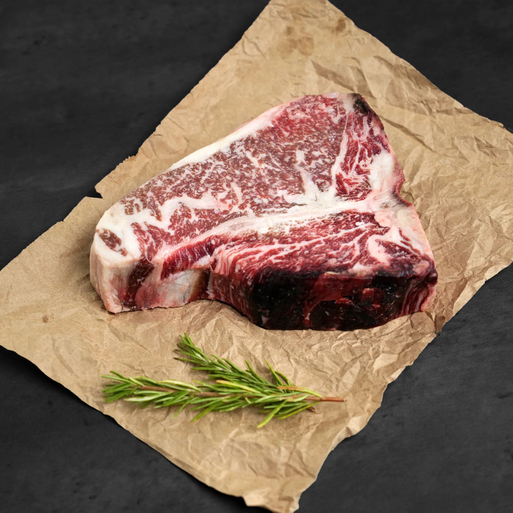 Raw steak on butchers paper with rosemary as garnish