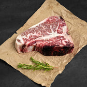 Raw steak on butchers paper with rosemary as garnish