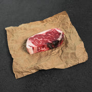 Raw steak on crumpled brown paper against a dark background