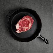 Raw bone in meat on black iron pan on a dark surface