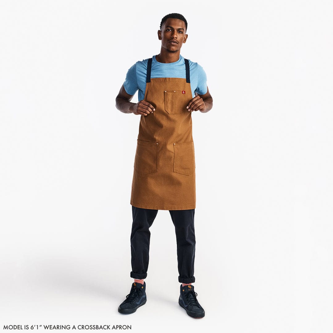 Brown crossback apron worn over a light blue shirt