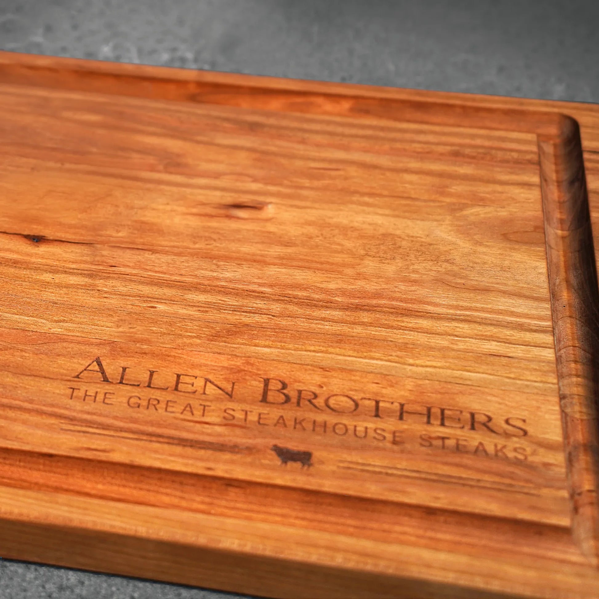 Cherry Wood Handcrafted Cutting Board with raised edge, Allen Brothers laser-etched, designed by Thomas Cannell, showcasing artisan quality for kitchen prep and presentation.