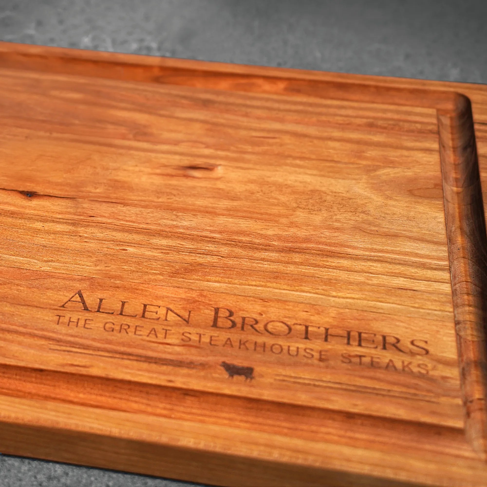 Cherry Wood Handcrafted Cutting Board with raised edge, Allen Brothers laser-etched, designed by Thomas Cannell, showcasing artisan quality for kitchen prep and presentation.