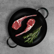 Double Cut Halal Australian Lamb Chop in a black cast-iron pan with rosemary, showcasing French-trimmed bone-in cuts for an elegant presentation.