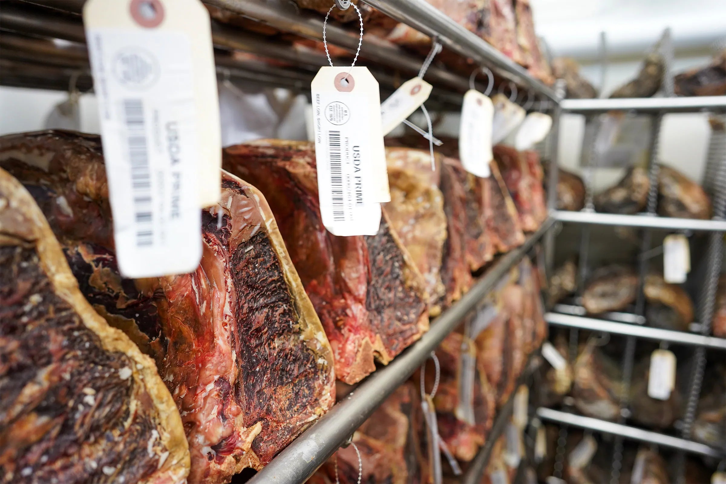 meat aging on metal racks with white tags hanging