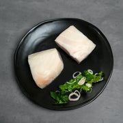 Raw Foley Chilean Sea Bass Filets on a black plate