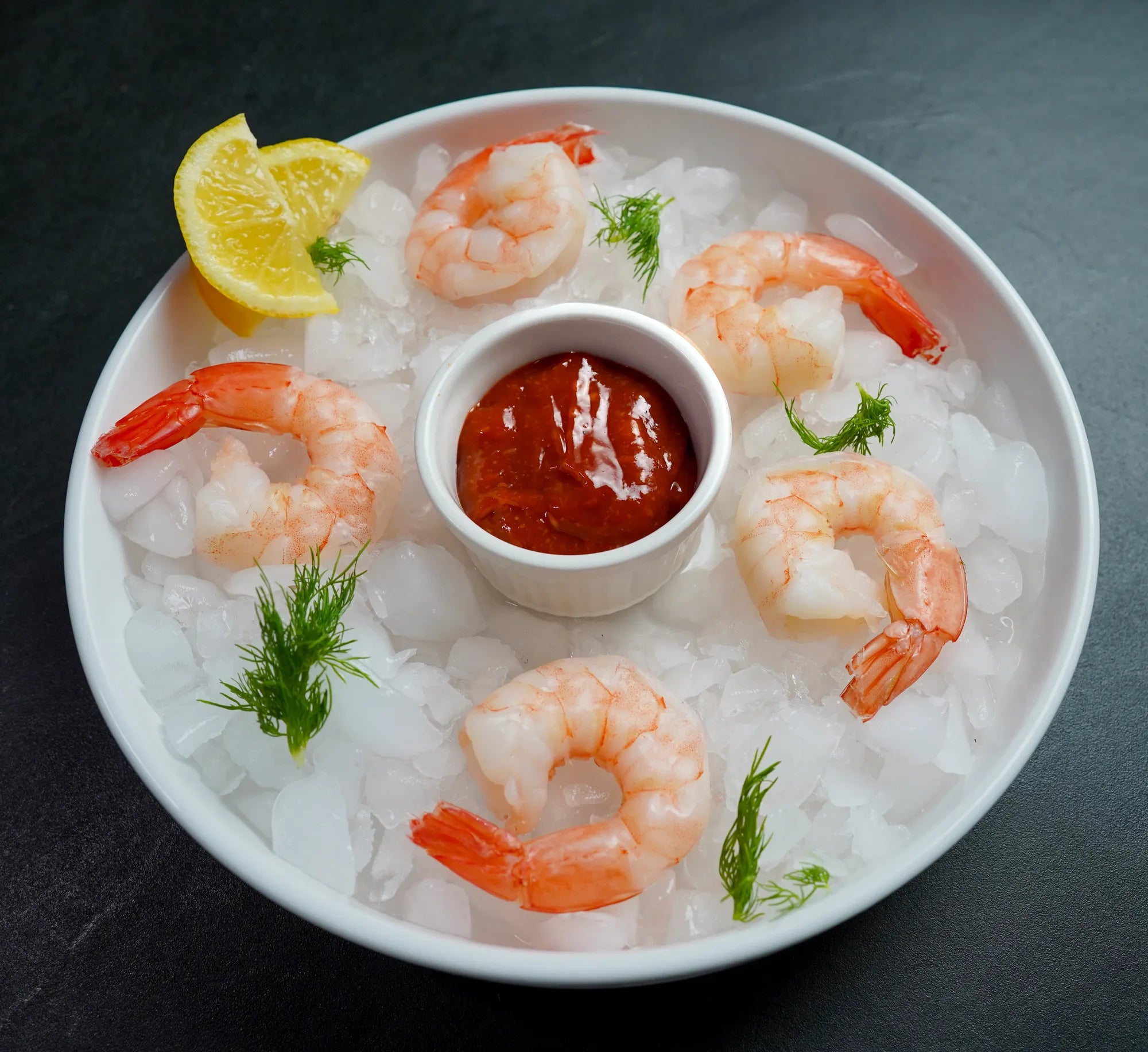 Foley Cooked Shrimp in a white bowl of ice with a  sliced lemon