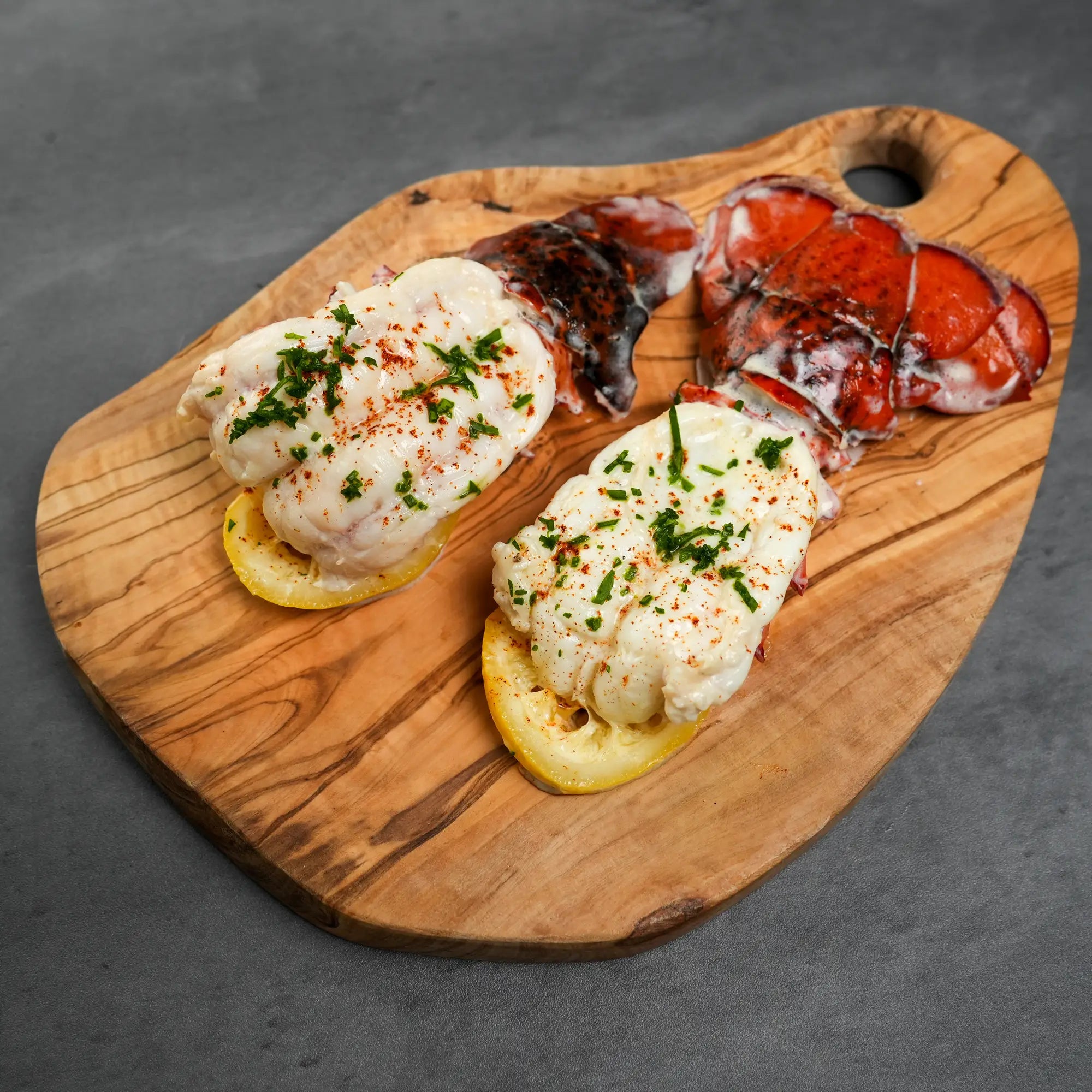 Wooden cutting board with lobster tailson a gray background