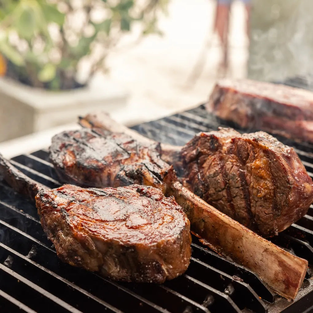 Grilled steaks on a barbecue grill with a blurred outdoor background