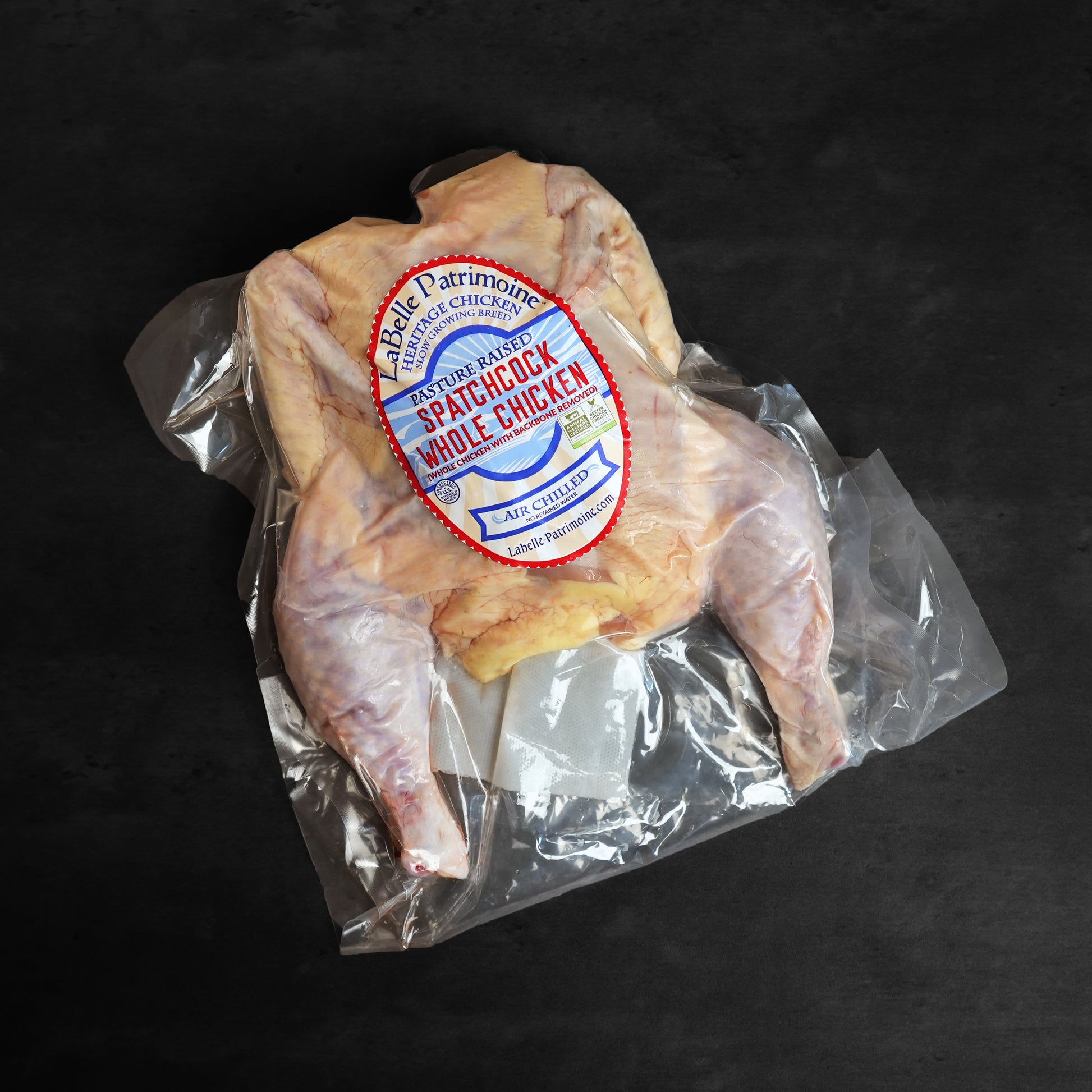 Raw LaBelle Patrimoine Spatchcock Whole Chicken in packaging on grey slate background