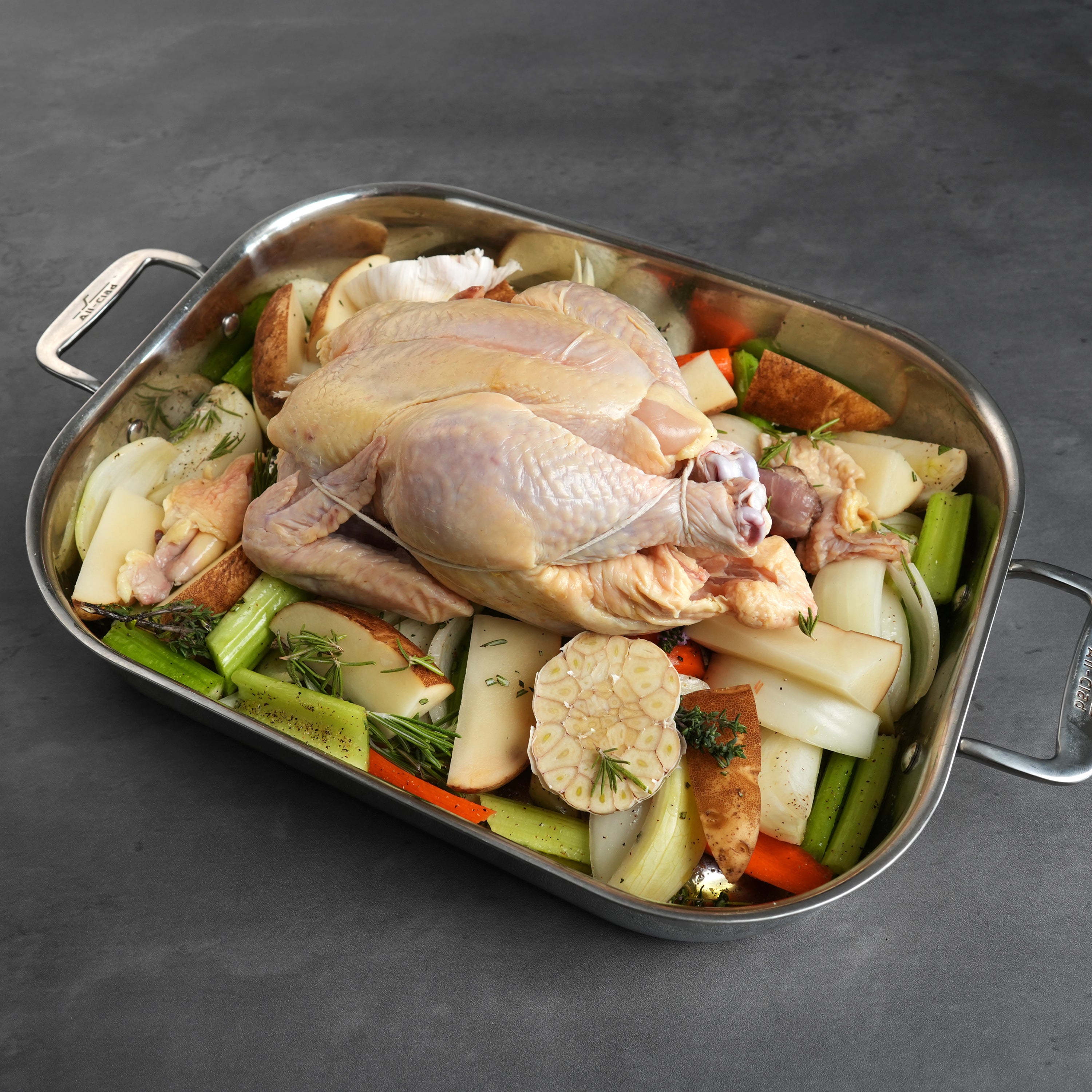 LaBelle Patrimoine Whole Chicken raw at an angle, tied up in a prep tray on a grey slate background
