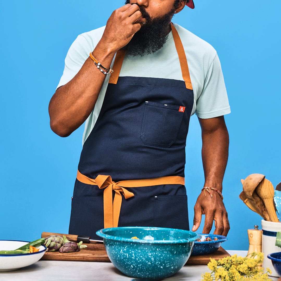 Midnight blue apron worn with front pocket and tan neck straps tied at the waist