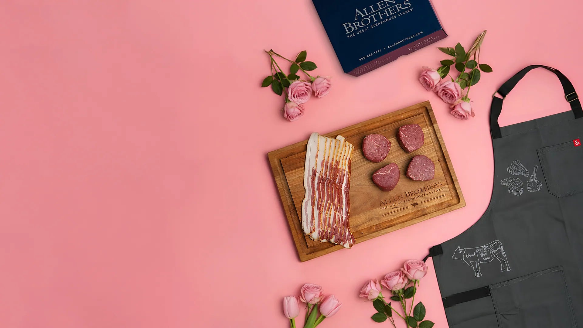 Butcher's display with meat products, a cutting board, and an apron on a pink background.