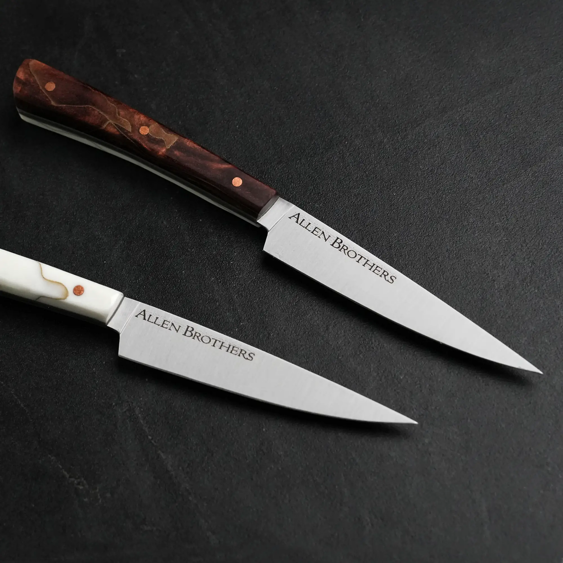 TH Blades Handcrafted Duality Paring Knife Set featuring Allen Brothers–branded blades, one with a dark wood handle, the other with a white composite handle.
