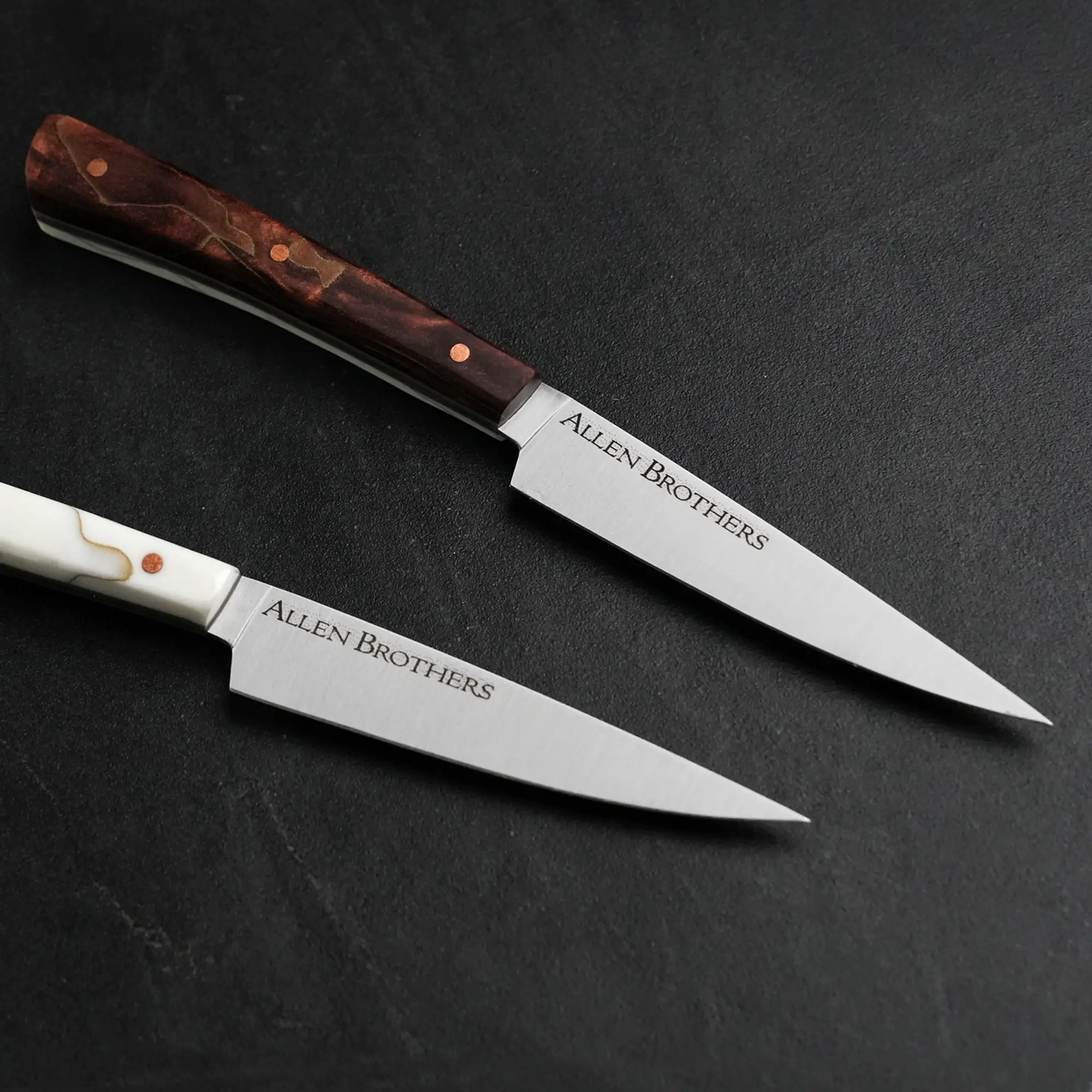 TH Blades Handcrafted Duality Paring Knife Set featuring Allen Brothers–branded blades, one with a dark wood handle, the other with a white composite handle.
