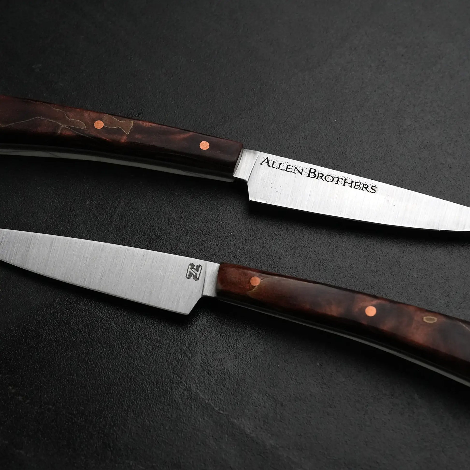 TH Blades Handcrafted Duality Paring Knife Set: two slender knives with stainless-steel blades and dark wooden handles, accented with copper rivets, crafted by Todd Harrington.