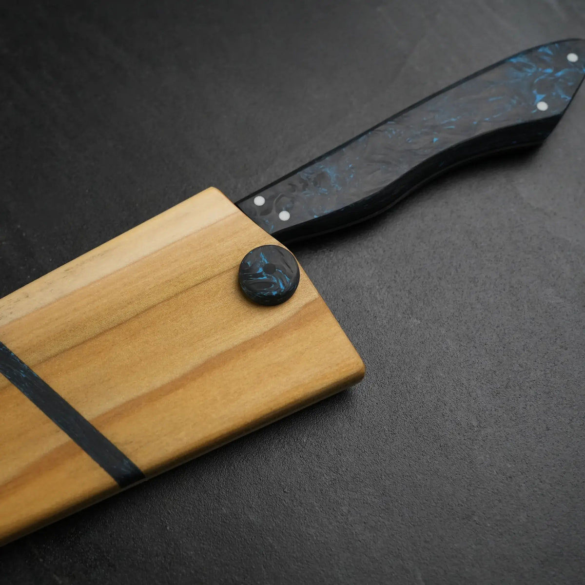 TH Blades Handcrafted 8 Chef Knife with a black-and-blue swirled resin handle, displayed with a matching wooden cutting board featuring a black resin inlay.