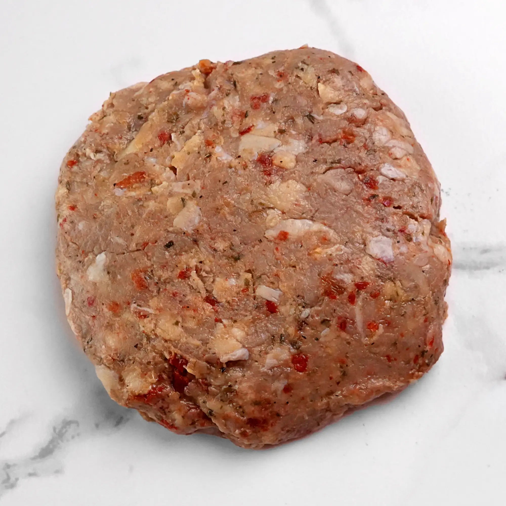 Turkey Burger: A raw, seasoned patty with bits of onion and red pepper, ready to grill for a flavorful and nutritious meal.