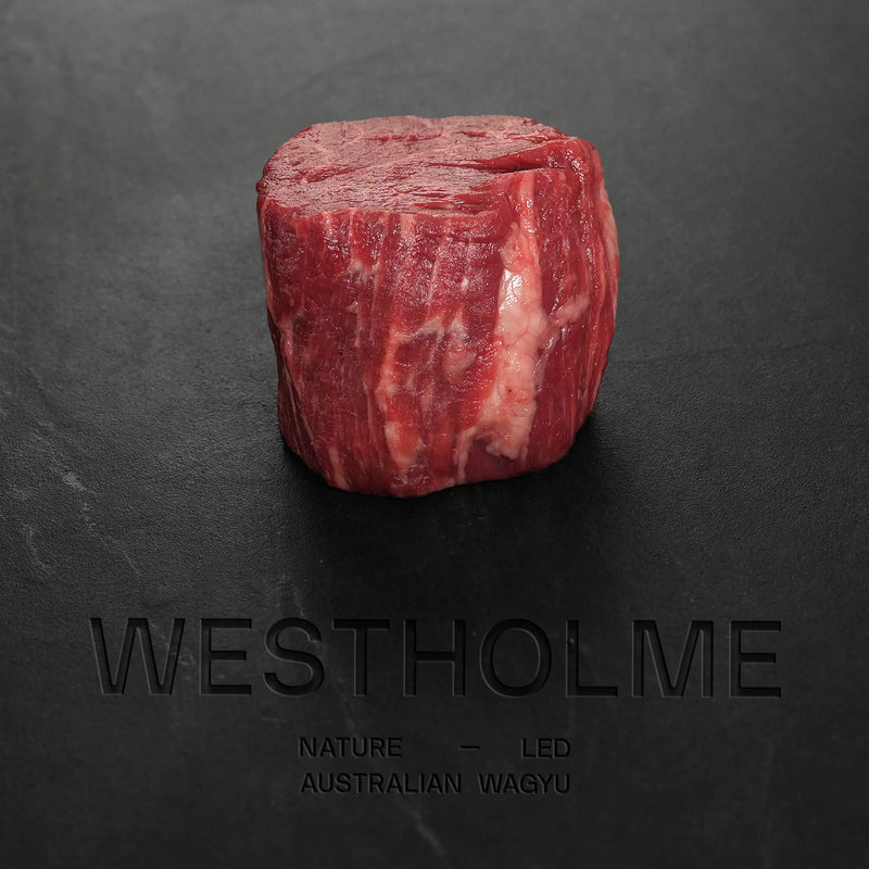 Westholme Australian Wagyu Steak Combo features a thick-cut raw steak with intense marbling, embossed branding visible, displayed on a dark surface.