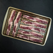 Westholme Australian Wagyu Halal Beef Bacon on a wire rack, showcasing marbled beef strips ready for seasoning, highlighting its richness and robust beefiness.