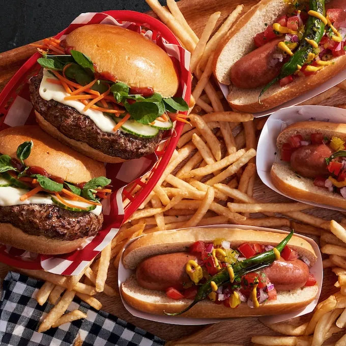 All-American Combo: Platter with juicy steak burgers and beef hot dogs, topped with fresh veggies, accompanied by golden fries, perfect for grilling occasions.
