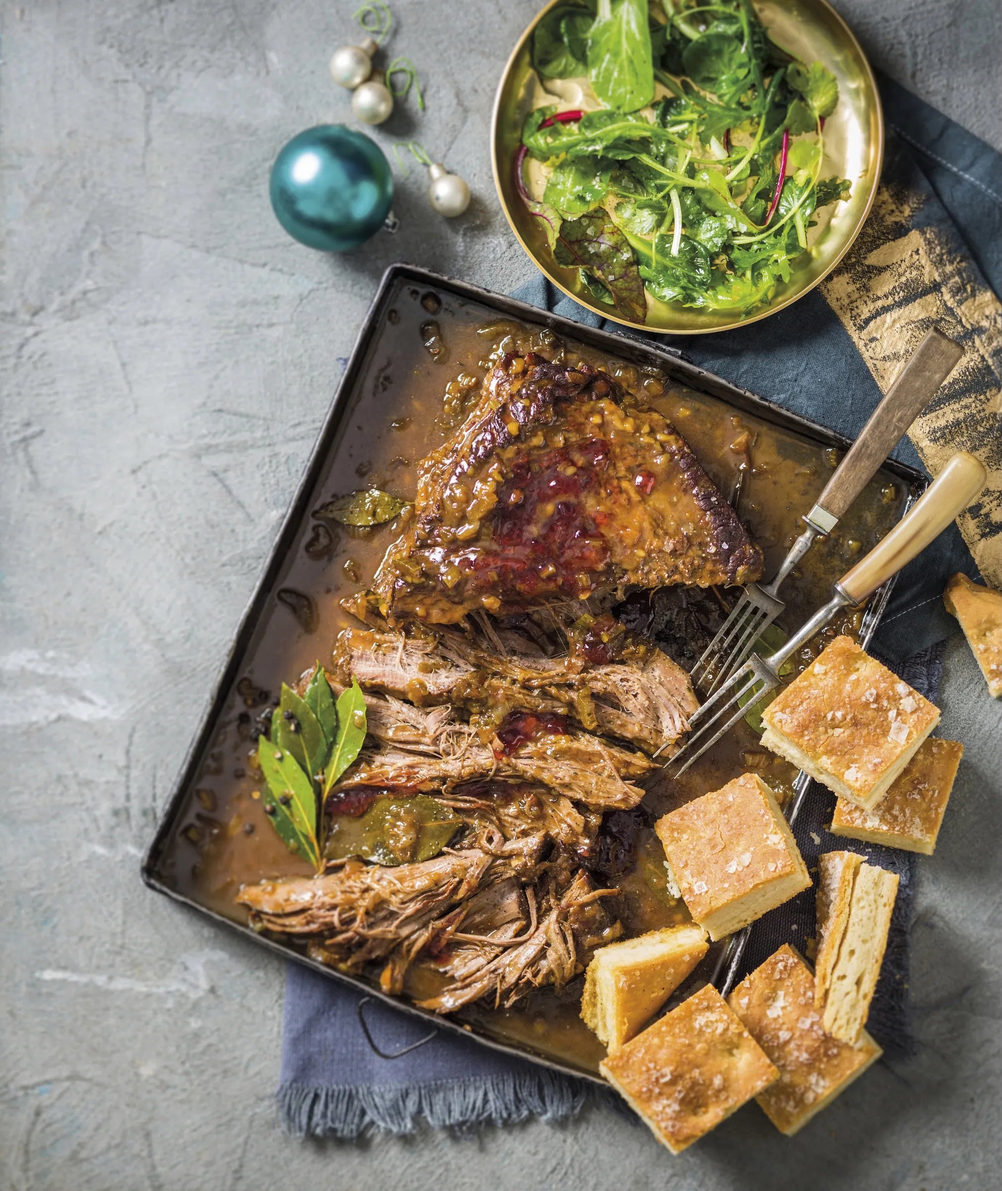 Cooked meat on square metal pan with bread and salad