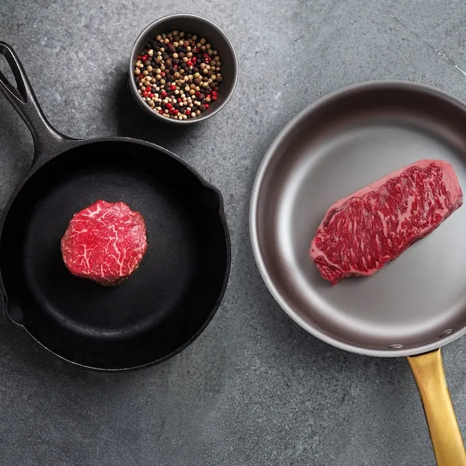 Prime Filet Mignon & New York Strip Combo displayed in pans, with a beef filet in cast-iron and a strip steak in nonstick, peppercorns above.
