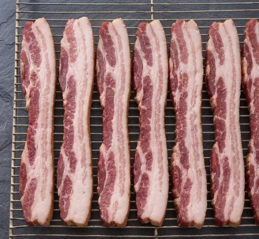 Westholme Australian Wagyu Halal Beef Bacon strips on a wire rack, uncooked, highlighting their rich beefiness, cured and smoked for a robust flavor.